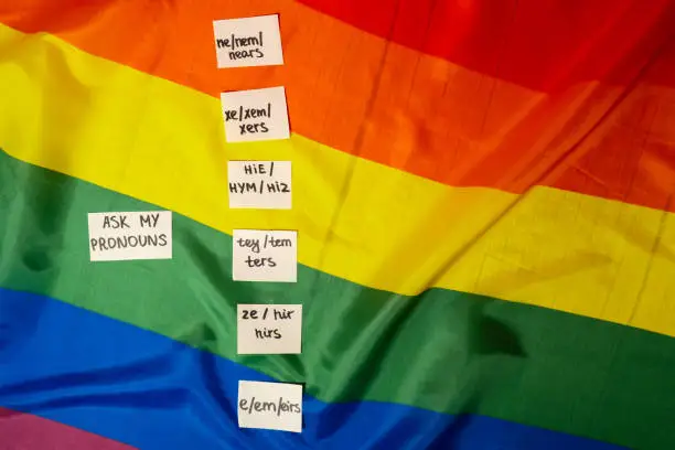 ASK MY PRONOUN Neo pronouns concept. Rainbow flag with paper notes text gender pronouns hie, e, ne, xe, ze, tey. Non-binary people rights transgenders. Lgbtq community support assume my gender, respect pronouns tolerance equal rights