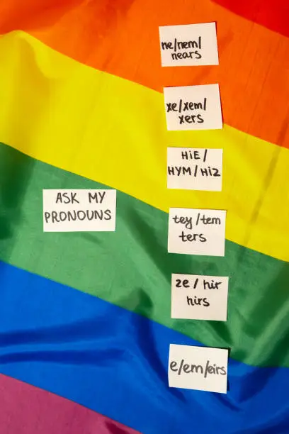 ASK MY PRONOUN Neo pronouns concept. Rainbow flag with paper notes text gender pronouns hie, e, ne, xe, ze, tey. Non-binary people rights transgenders. Lgbtq community support assume my gender, respect pronouns tolerance equal rights