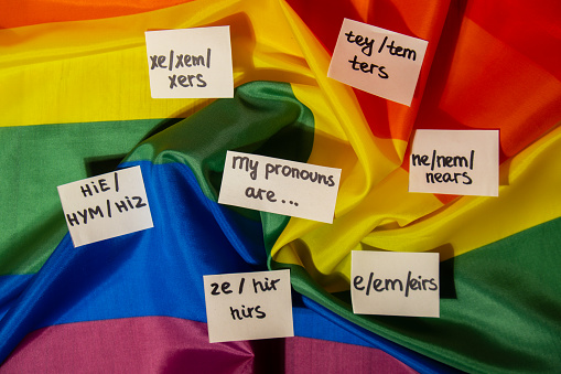 MY PRONOUNS ARE Neo pronouns concept. Rainbow flag with paper notes text gender pronouns hie, e, ne, xe, ze, tey. Non-binary people rights transgenders. Lgbtq community support assume my gender, respect pronouns tolerance equal rights