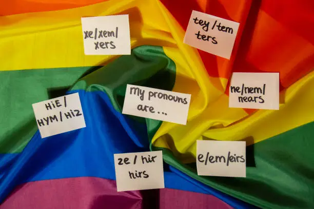 MY PRONOUNS ARE Neo pronouns concept. Rainbow flag with paper notes text gender pronouns hie, e, ne, xe, ze, tey. Non-binary people rights transgenders. Lgbtq community support assume my gender, respect pronouns tolerance equal rights