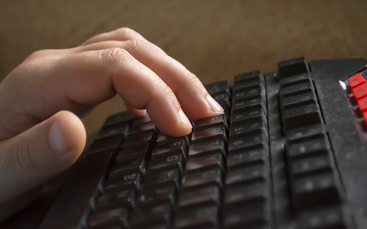A man's hand on the keyboard. the man prints the text. Fingers indent the keys of the keyboard. Tex set.