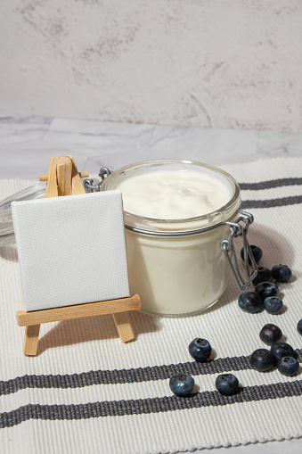 Glass jar with natural organic homemade yogurt and blueberries on table. Immunity-boosting ingredients. Concept of healthy eating breakfast of Greek yogurt in glass jar and fresh blueberries Copy space empty note. Fermenting superfood