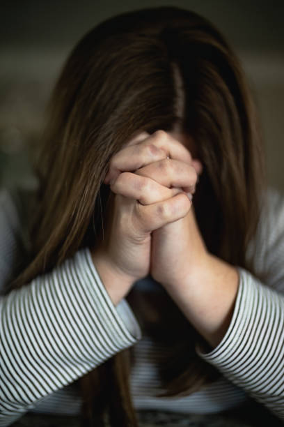 istock Young woman praying in home alone 1476750550