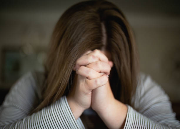 istock Young woman praying in home alone 1476750551