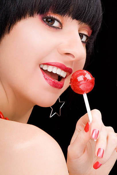 istock sweet woman with candy on black background 147675106