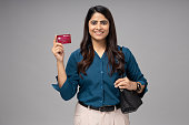 Portrait of young businesswoman showing smart card for travel on gray background stoke photo