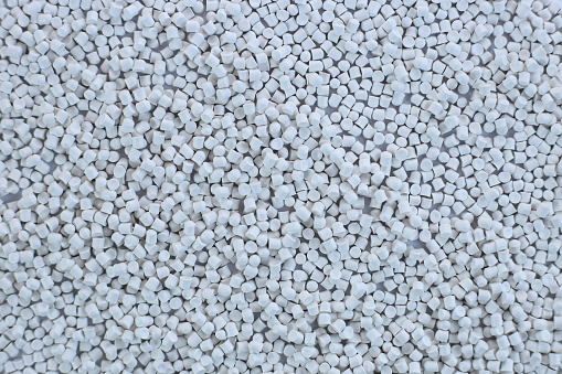 Close-up of white plastic polymer granules. polymer plastic. compound polymer. PVC resin compounds. Tinted plastic granulate for injection moulding process.