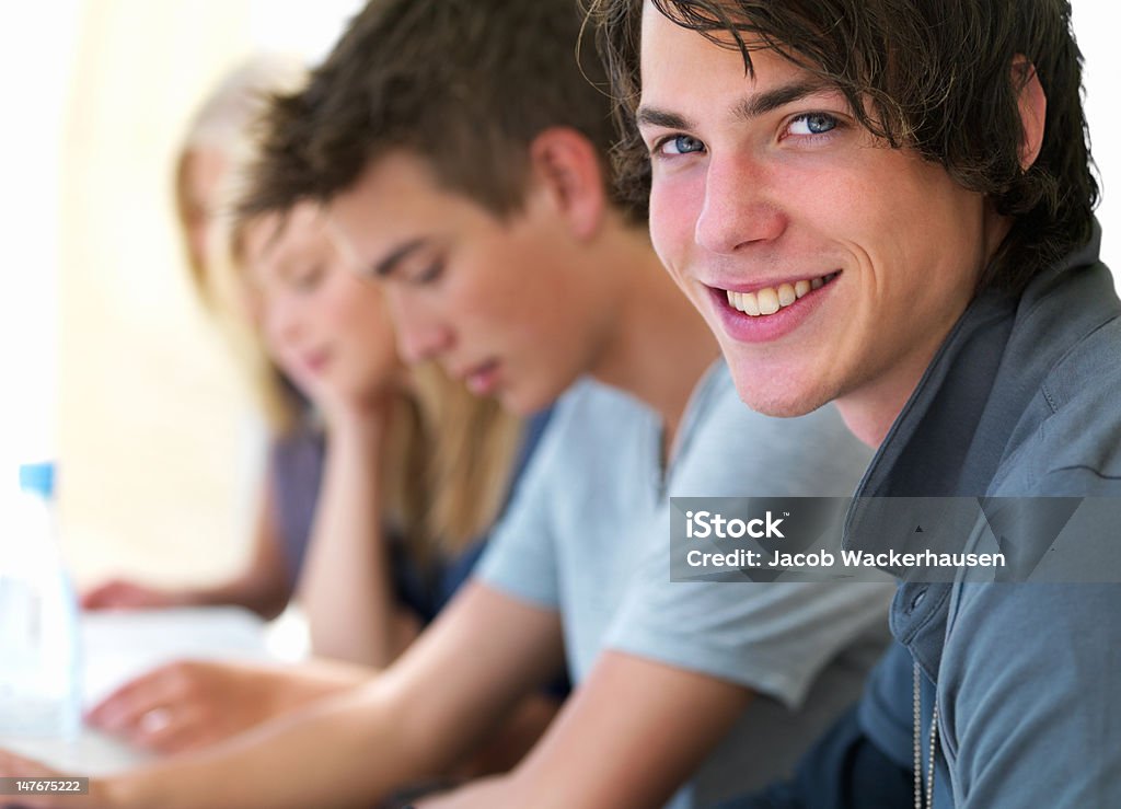 Close-up de feliz adolescente sentado con amigos en la sala de montaje tipo aula - Foto de stock de Adolescente libre de derechos