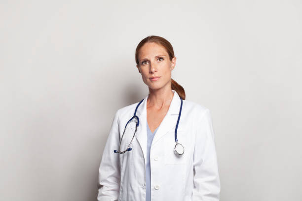 istock Serious friendly doctor or nurse with stethoscope wearing white lab coat uniform standing indoors 1476754644
