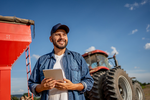 Portrait of farmer with tablet in front of his tractor