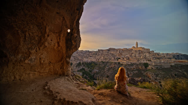 Woman looking at ancient Sassi di Matera against sky on mountain
