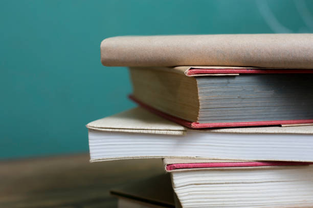 istock Textbooks on wooden school desk with chalkboard in background. 1476764792