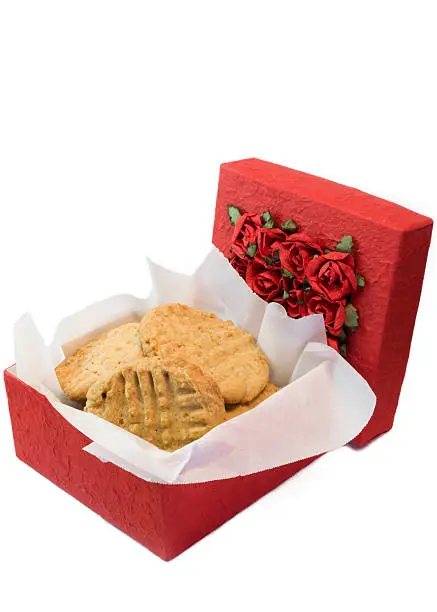 A gift of homemade peanut butter cookies is displayed in an open red box.  The box top is covered with paper roses.