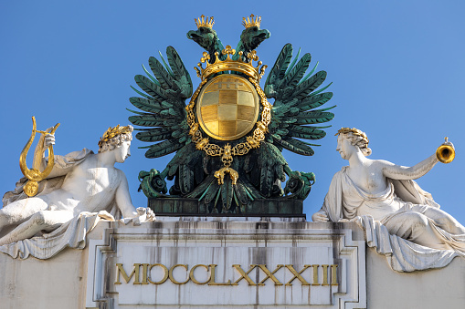 Habsburg two-headed eagle with the Order of the Golden Fleece in bronze and gold with white stone statues above main entrance of Palais Pallavicini on Joseph square in Vienna