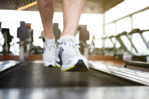 Low section of man jogging on treadmill, front view