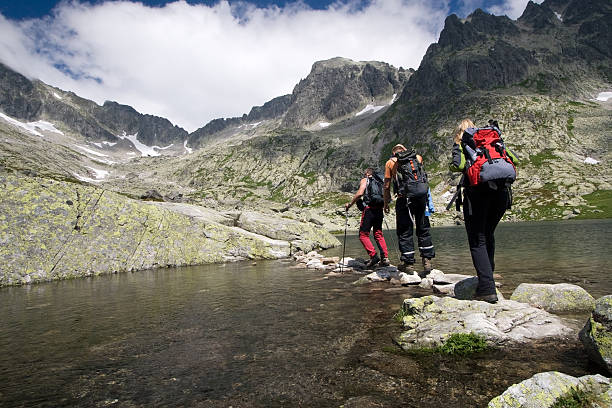 Hiking in high mountains Group of people crossing mountain pond in Tatra Mountains, Slovakia tatra tourists stock pictures, royalty-free photos & images