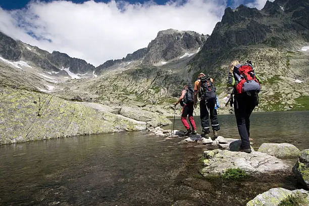 Group of people crossing mountain pond in Tatra Mountains, Slovakia