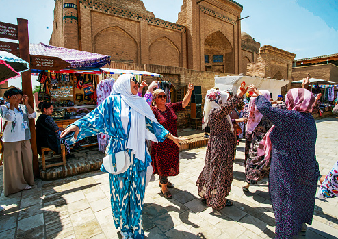 05-12-2022 Khiva Uzbekistan. Dancing in the Old City (Medina) in Khiva to the music . Young woman in blue dancing  enjpying