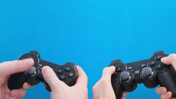 istock Husband and wife playing a game using a wireless controller on a blue background close-up. 1476769067