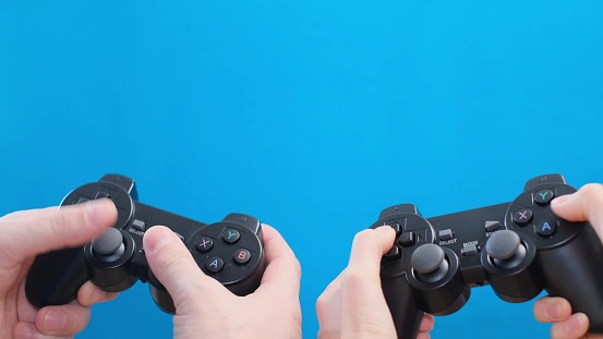 Husband and wife playing a game using a wireless controller on a blue background close-up. 4k video