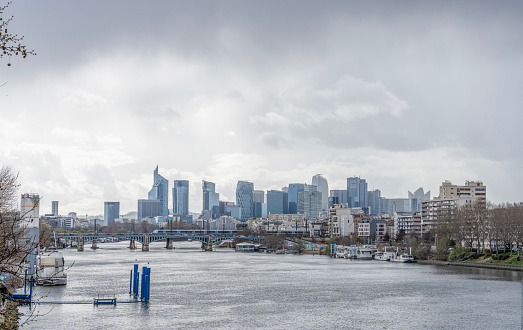 Gennevilliers, France - 03 26 2023: Panoramic view of La Defense towers district from Gennevilliers bridge with cloudy weather