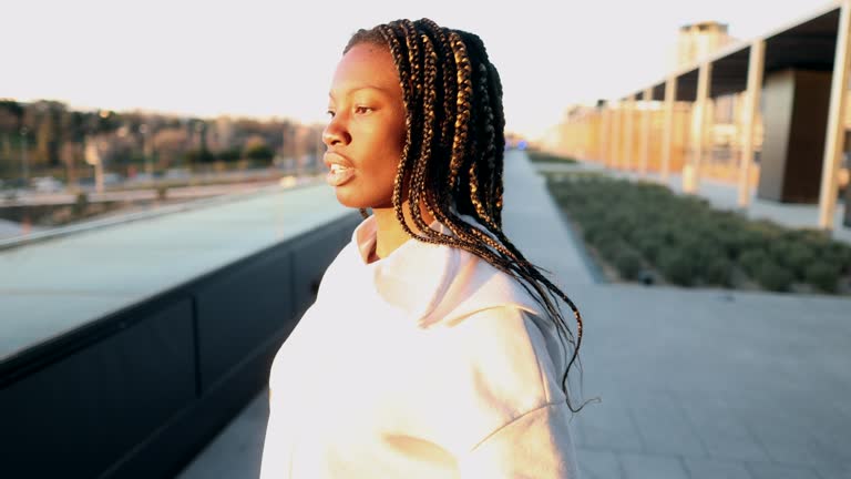 Silhouetted against a backdrop of city skyscrapers and the warm glow of a setting sun, the pretty African American woman radiated confidence and beauty