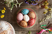 Colorful Easter eggs decorated with wax, with spring flowers and Easter pastry