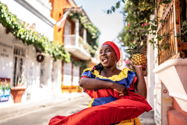 Palenquera walking and dancing on the street in Cartagena, Colombia Palenquera walking and dancing on the street in Cartagena, Colombia traditional song stock pictures, royalty-free photos & images