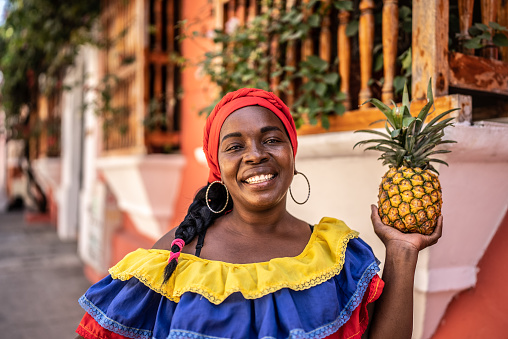 Portrait of a mature palenquera holding a pineapple on the street in Cartagena
