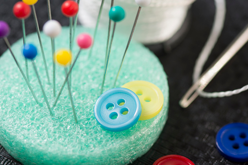 Sewing buttons to clothes with a needle and thread.