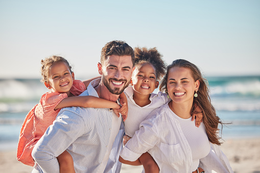 Happy family, beach portrait and smile on vacation, holiday or summer trip in Brazil. Relax, travel and caring mom, dad and girls walking with piggy back and bonding on ocean, sea and sandy shore.