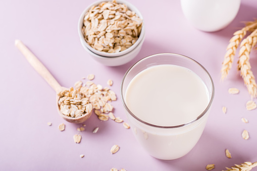 A glass of fresh oat milk and oatmeal. Vegan dairy-free organic drink.