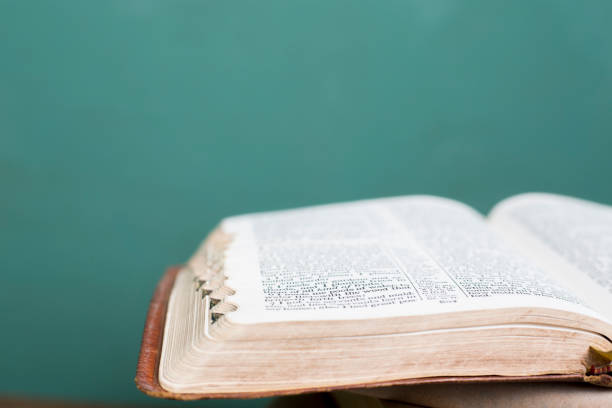 pilas de biblias y libros de referencia para estudios espirituales.  las biblias en primer plano están abiertas a varias escrituras. - open book teaching table fotografías e imágenes de stock