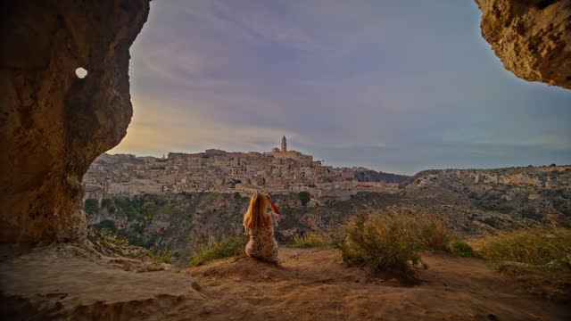 Tourist looking at ancient Sassi di Matera against sky on mountain