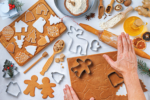 Christmas gingerbread different shaped with ingredients for gingerbread and the hands of a woman baker, top view, flat lay