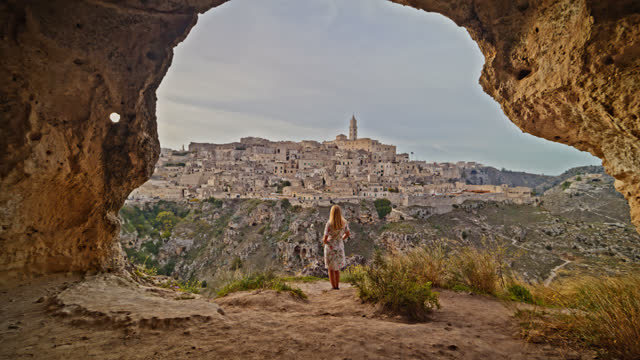 Woman looking at Sassi di Matera while standing at cave