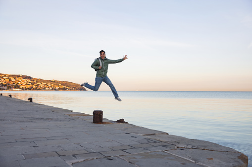 Ecstatic Male Tourist Jumping At The Seaside In Early Morning