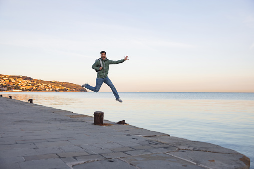 Photo of an adventurous young boy jumping off a big rock into the sea