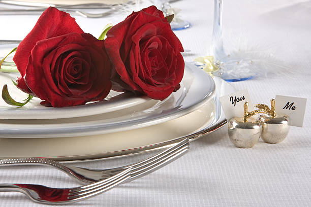Two red roses lay on a white plate with You and Me placards