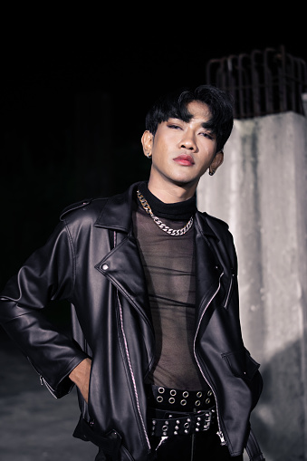 an asian man in a black leather jacket posing like a motorcycle gang in an old building