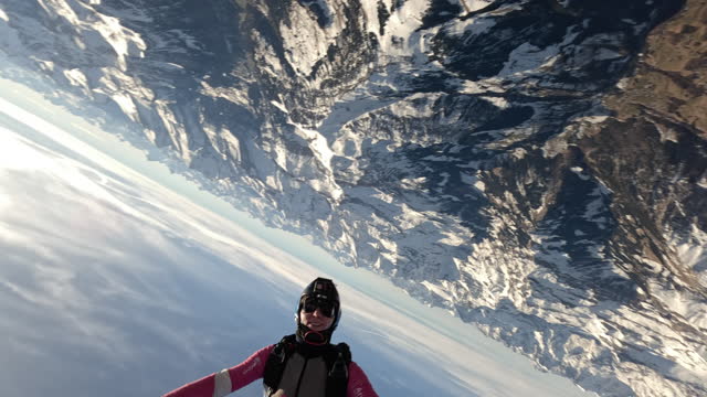 Female skydiver soars above Swiss mountain landscape