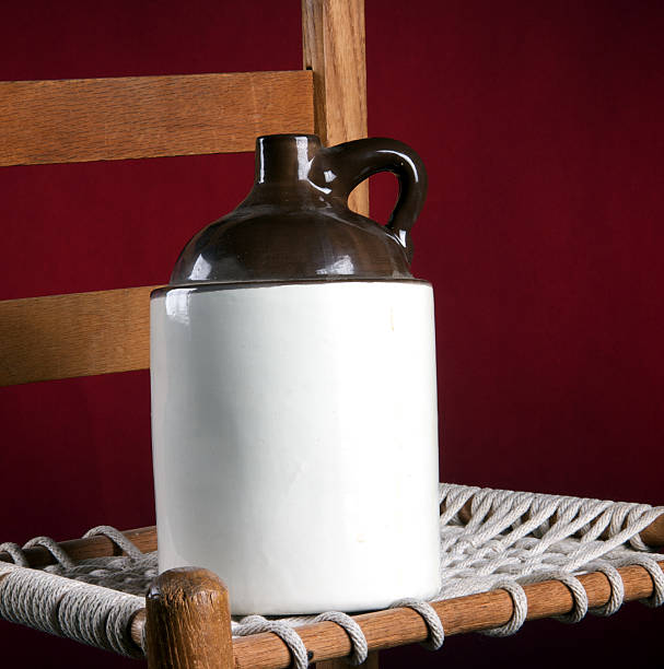 An old pottery ceramic country jug and rope bottom chair on a red background in the square format  with copy space.