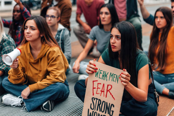 istock young crowd sitting on street protesting for gender equality - panel with weak men fear strong women 1476810321