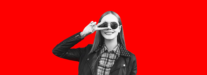 Fashion portrait of happy smiling blonde woman in rock black style on red background