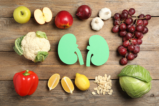 Flat lay composition with paper cutout of kidneys and different products on wooden table