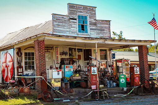 Vesta, VA, USA - October 18, 2021: An eclectic mix of old and vintage gas station pumps, signs, vending machines and garden implements are displayed around the front porch of a rural shop.
