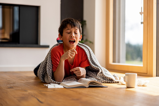 Boy Sneezing While Reading A Book
