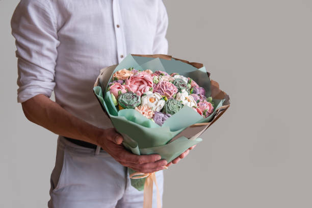 顔のない男はマシュマロの甘い花の花束を手に持っている。シュガーレスバラ、ホビーベーキング - single flower flower red daisy ストックフォトと画像
