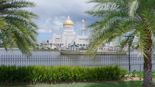 Sultan Omar Ali Saifuddien Mosque in Bandar Seri Begawan, Brunei Darussalam at daytime as seen from the Brunei river, cinematic view from park with palm trees.