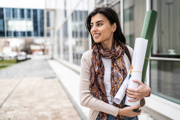 istock Campus life. University student holding blueprint papers outdoors 1476836132